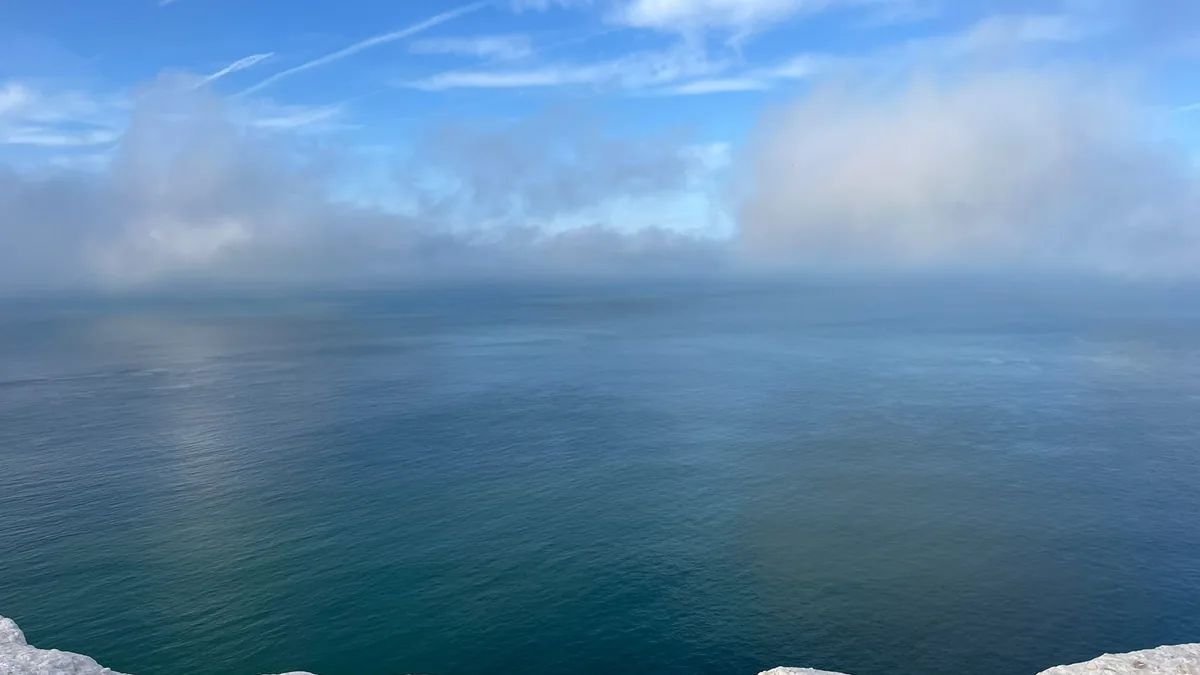 The sea seen from a chalk cliff, low cloud lying along the horizon